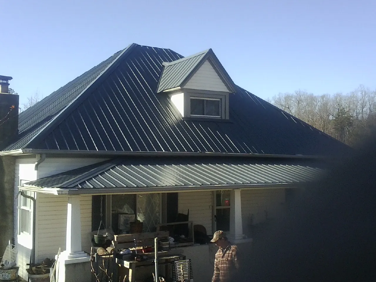 Dark blue standing seam metal roof with a dormer above a front porch in Ten Sleep
