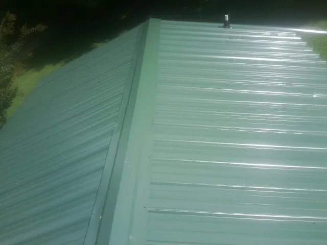New green metal panels meeting at the ridge of a roof — Flat Roof Repair work by our crew in Ten Sleep
