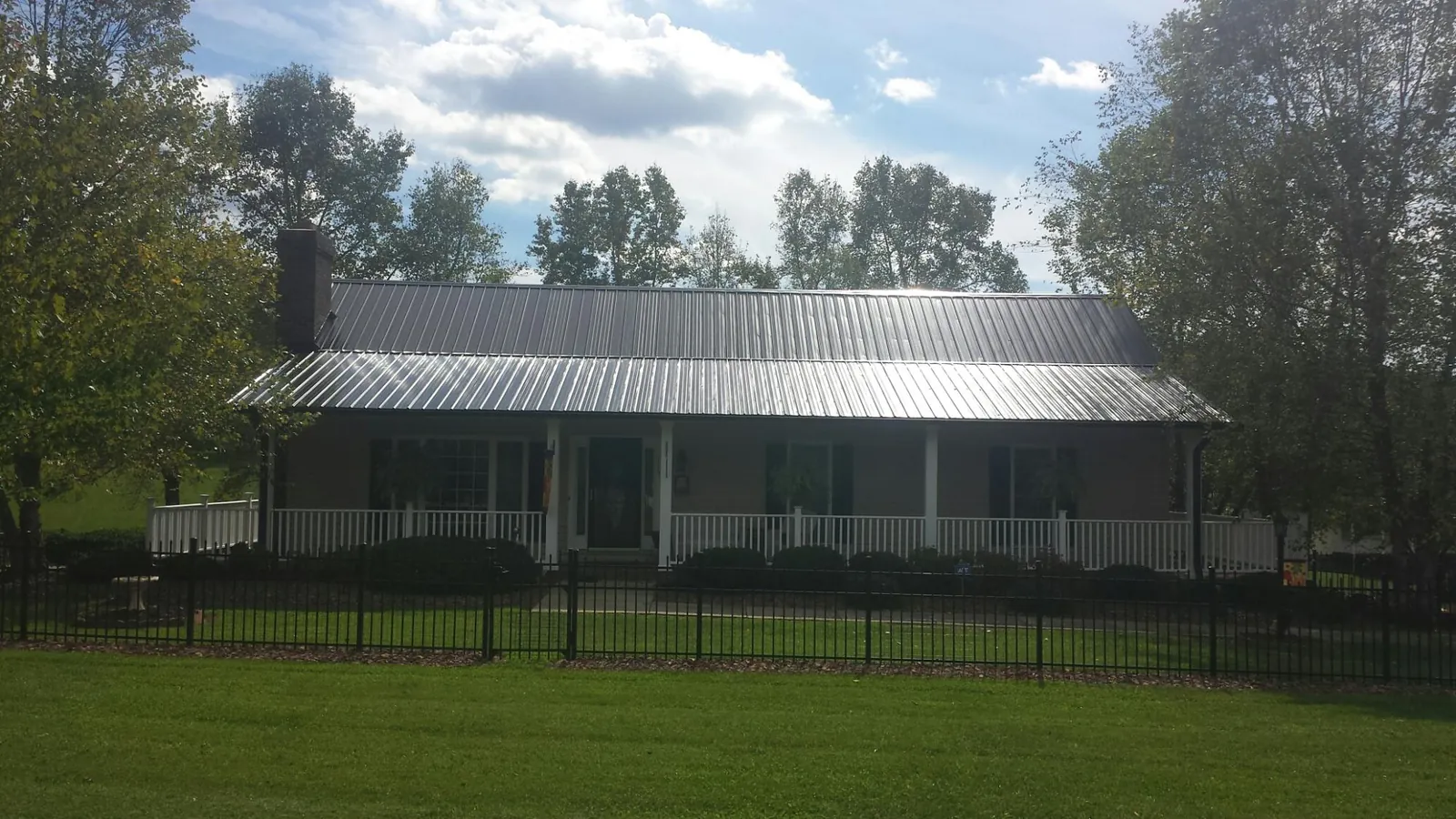 Gray metal roof on a brick ranch with a full width front porch — Gutter Guard Installation work by our crew in Ten Sleep