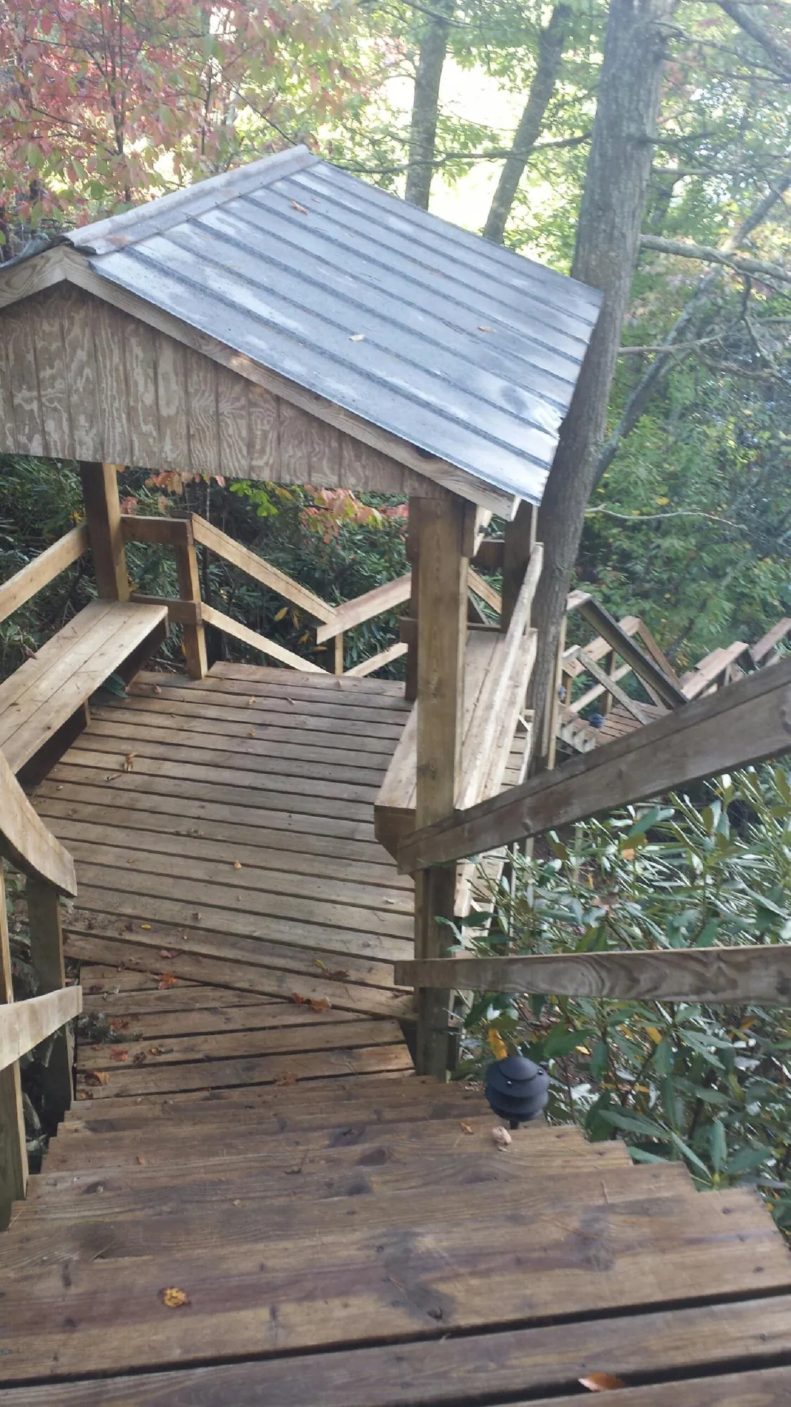 Metal roofed shelter over wooden steps on a wooded walkway — Skylight Repair & Installation work by our crew in Ten Sleep