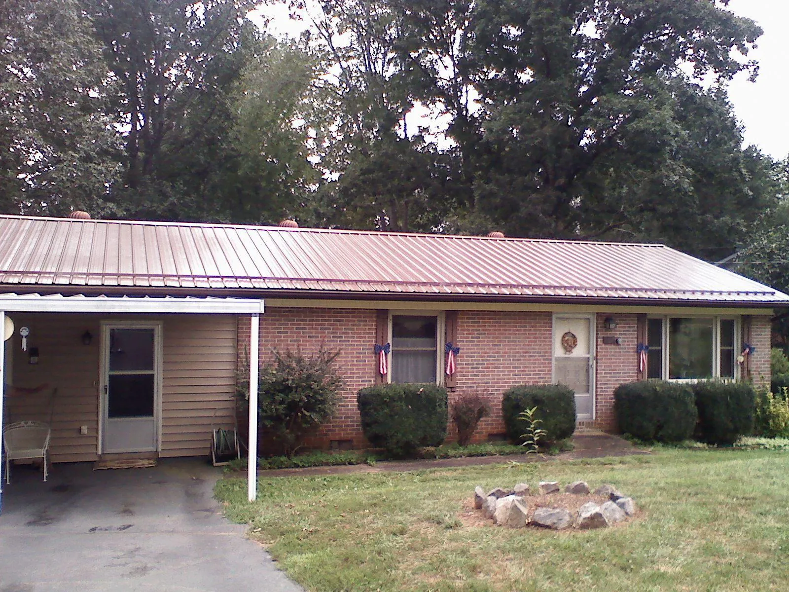 Bronze metal roof and carport on a brick ranch home — Roof Repair work by our crew in Ten Sleep
