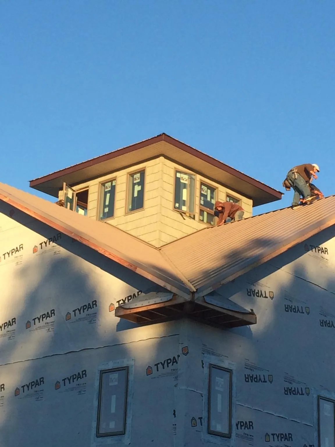 Roofers working around a rooftop cupola on a new metal roof at sunset — Roof Waterproofing in Ten Sleep by Roofing Brothers